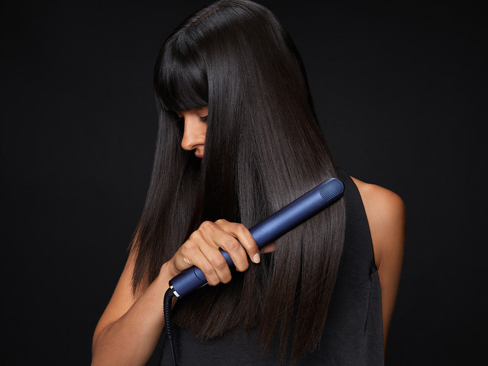 Model using a blue 2-in-1 Contouring Iron Pro hair straightener through black hair.