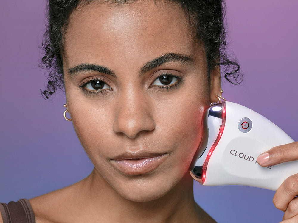 Model holding the Revive Beauty Device against her jaw line with red mode on.