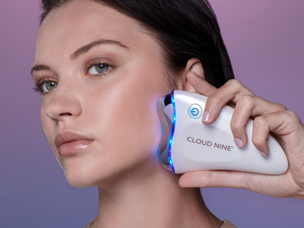 Model using the Revive Beauty Device on her jawline with blue light setting on.