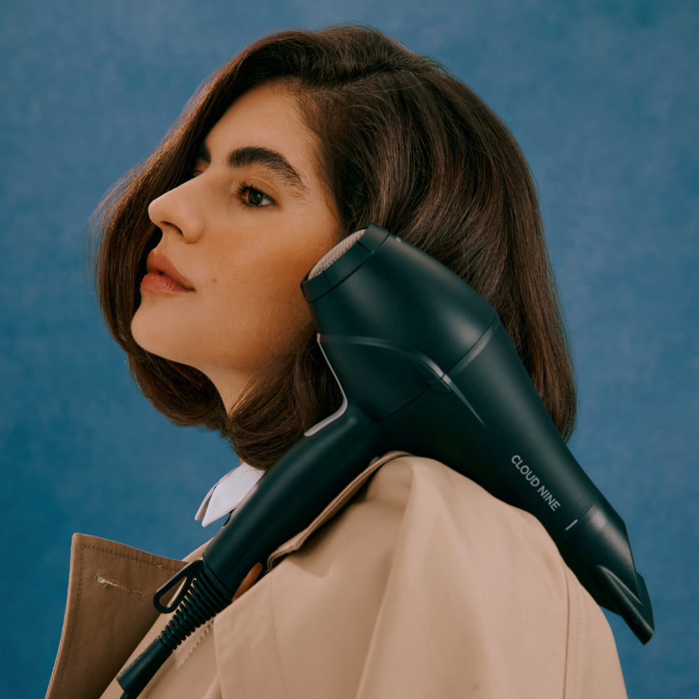 Brunette woman posing with Airshot hair dryer in Black on her shoulder – showcasing the attachment and Cloud Nine branding.