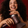 Woman with curly hair holding an Airshot Pro hair dryer with 'Cloud Nine' branding against a red background.