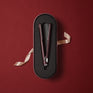 The Original Iron in a Dark Burgundy finish, laid on a matching case, displayed on a red background with a decorative pink bow.
