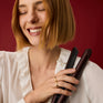 Smiling woman with a bob holding The Wide Iron in Dark Burgundy, in front of a red background.