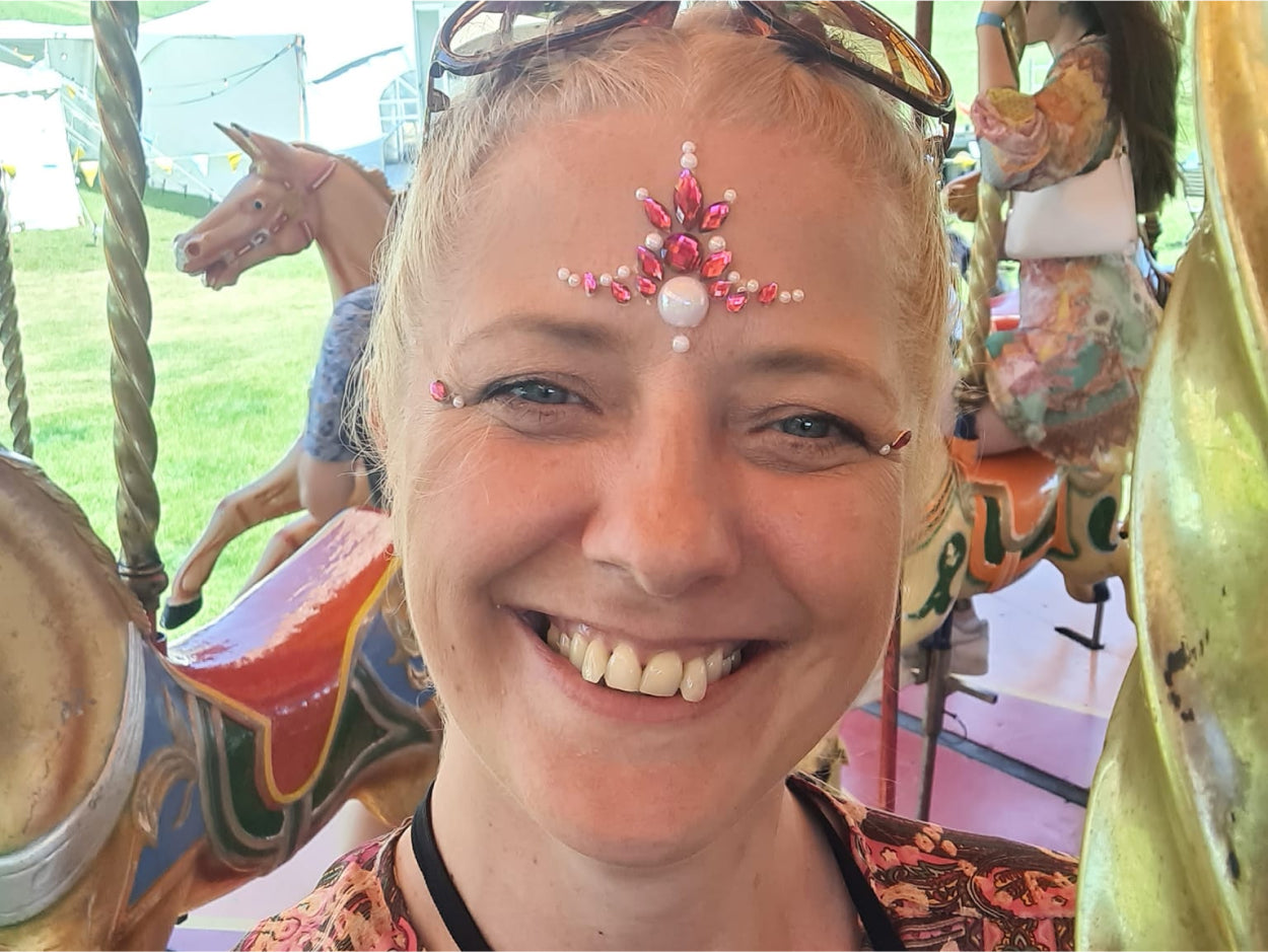 picture of a female CLOUD NINE employee smiling with gems stuck on her forehead 
