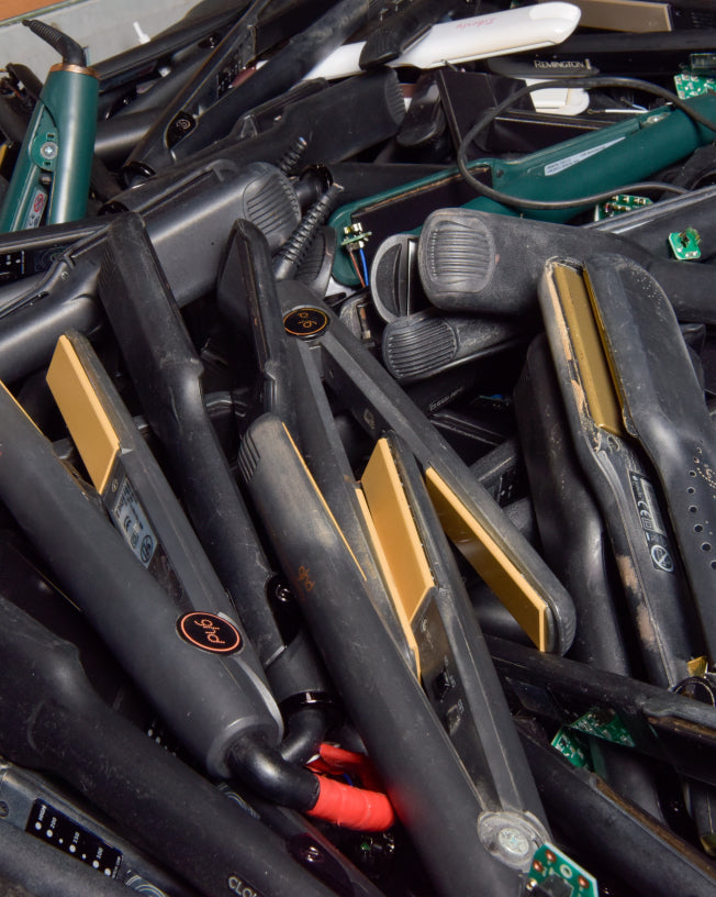 A pile of old hair straighteners that are ready to be recycled by CLOUD NINE.
