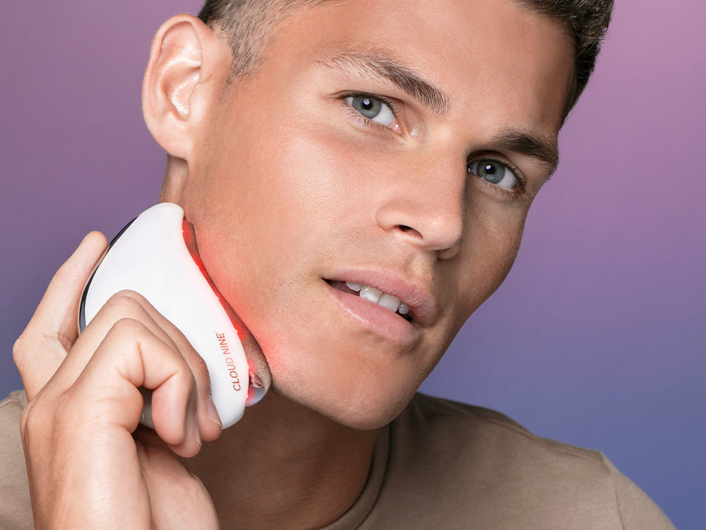 Male model holds Redefine against jaw line with Red Light Therapy turned on.