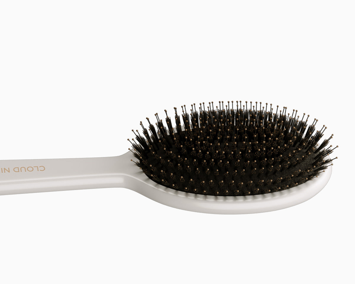 An image of the white CLOUD NINE Dressing Brush placed horizontally on a white background.